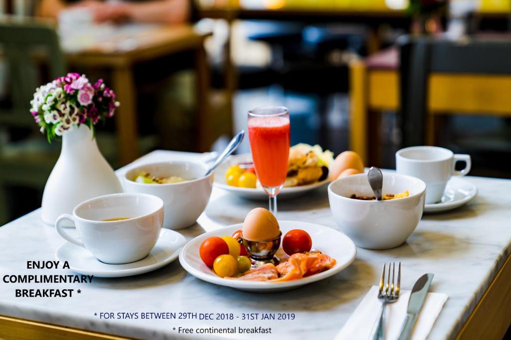 a table with plates of food and cups of coffee at Caftop Aparthotels Wenlock Manchester in Manchester