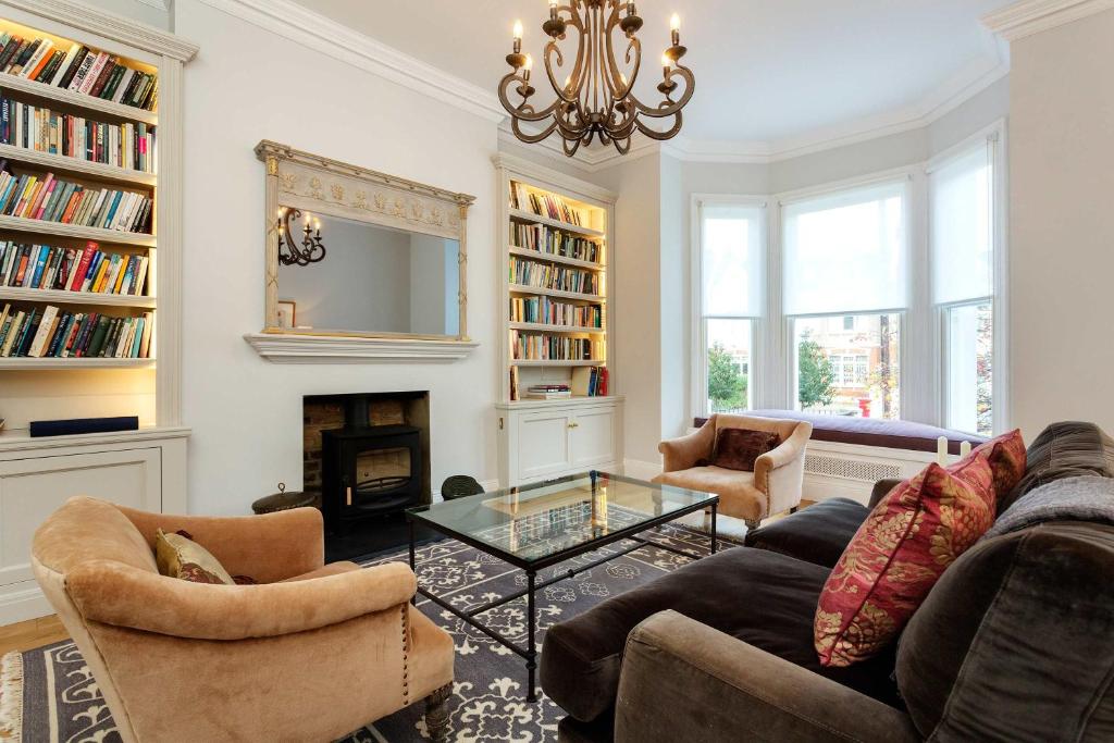 ein Wohnzimmer mit einem Sofa, Stühlen und einem Kamin in der Unterkunft Veeve - Southside Charm in London