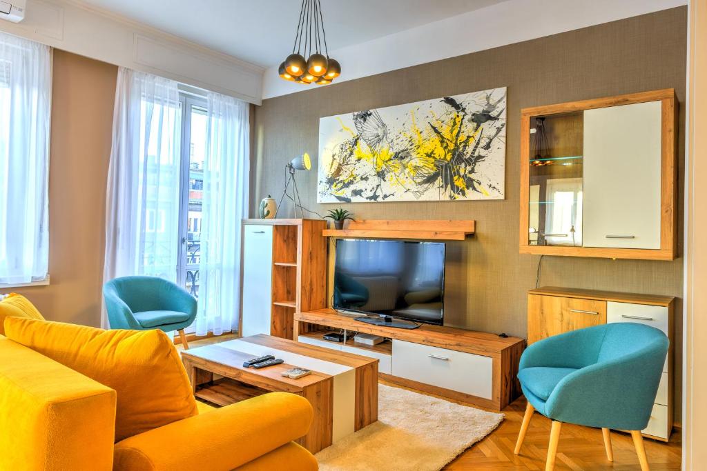 ein Wohnzimmer mit einem gelben Sofa und einem TV in der Unterkunft Central Capital Apartments in Budapest