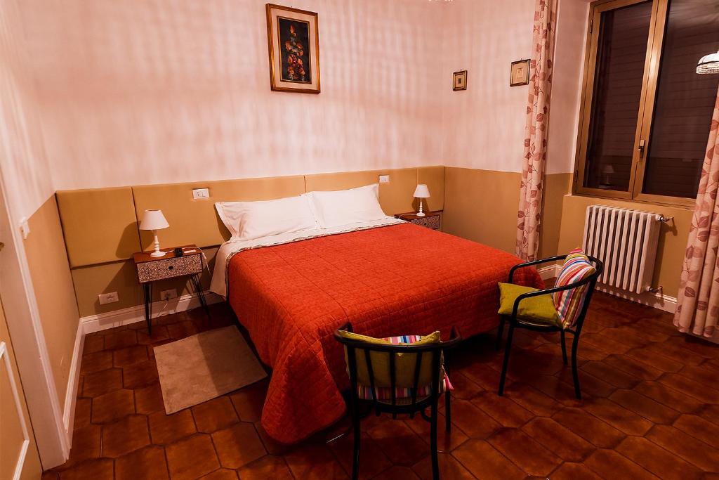 a bedroom with a bed with a red blanket and two chairs at Villa dei Pescatori in LʼAquila