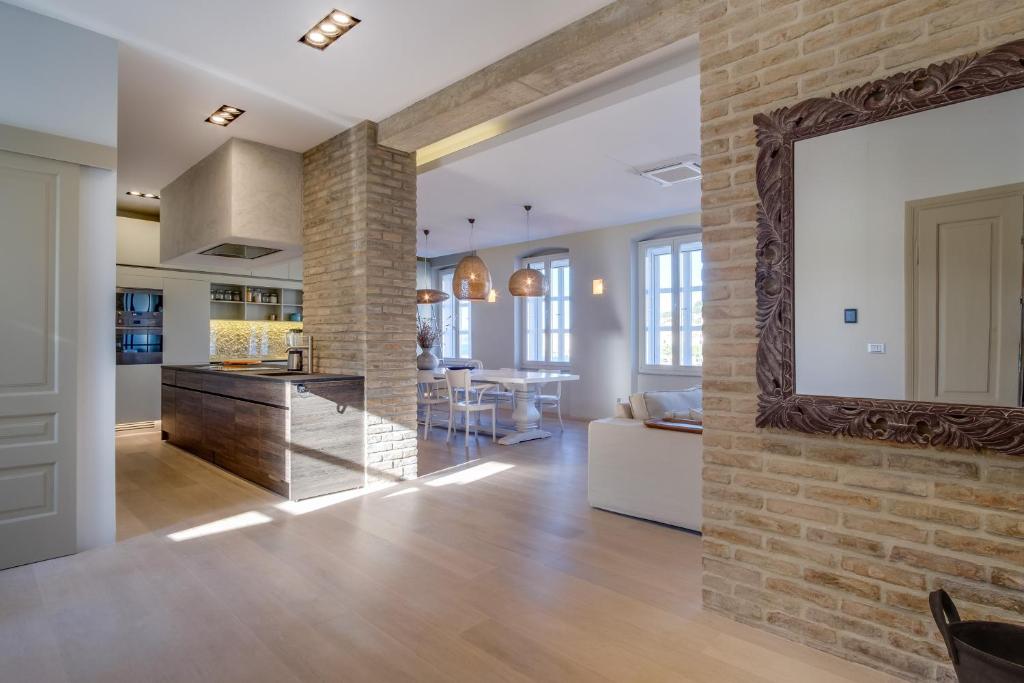 a kitchen and living room with a mirror on a brick wall at Apartments Argemonia in Mali Lošinj