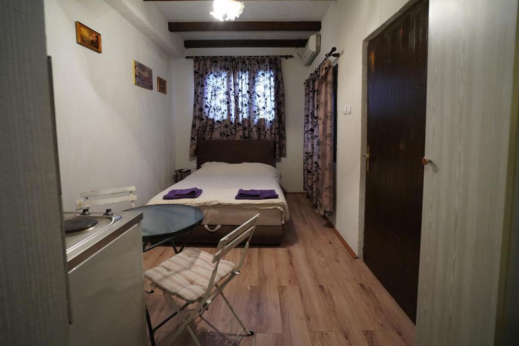 Habitación pequeña con cama, mesa y lavabo. en Apartman Rale, en Belgrado