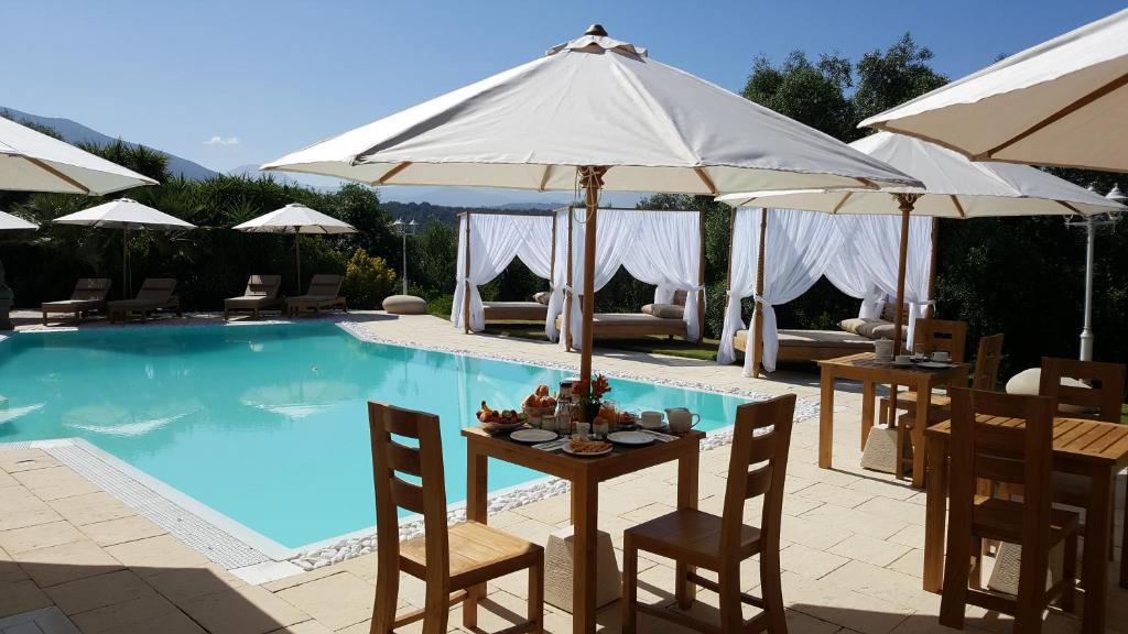 a pool with tables and umbrellas and a table with chairs at Villa Torrella in Mezzavia