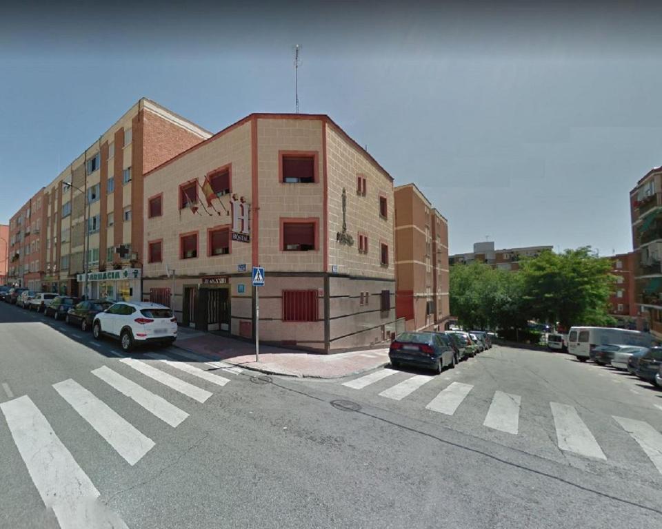 an empty street with cars parked in front of a building at Hostal Juan XXIII in San Sebastián de los Reyes