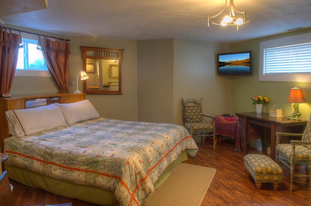 a bedroom with a bed and a table and a desk at Heartwood Inn in Drumheller