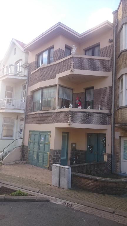 un edificio de apartamentos con puertas verdes y balcón en Le Rusticka, en De Panne