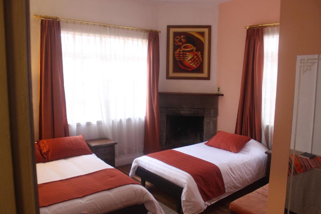 a bedroom with two beds and a fireplace and a window at Hotel Andino in Quito