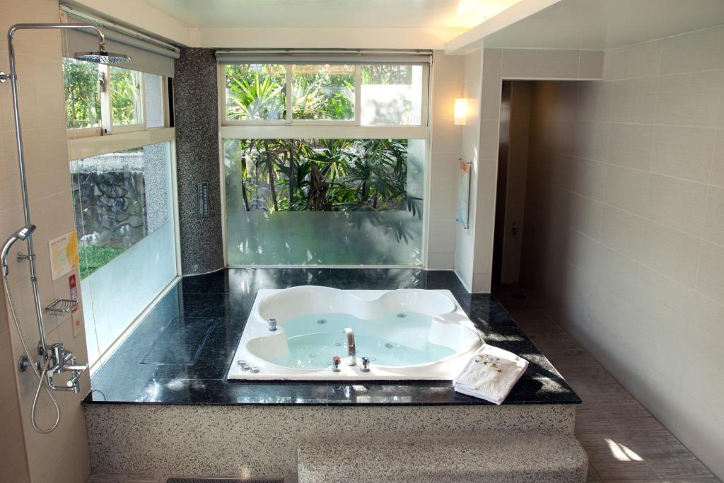 a bathroom with a bath tub and a window at Guanziling Lin Kuei Yuan Hot Spring Resort in Baihe