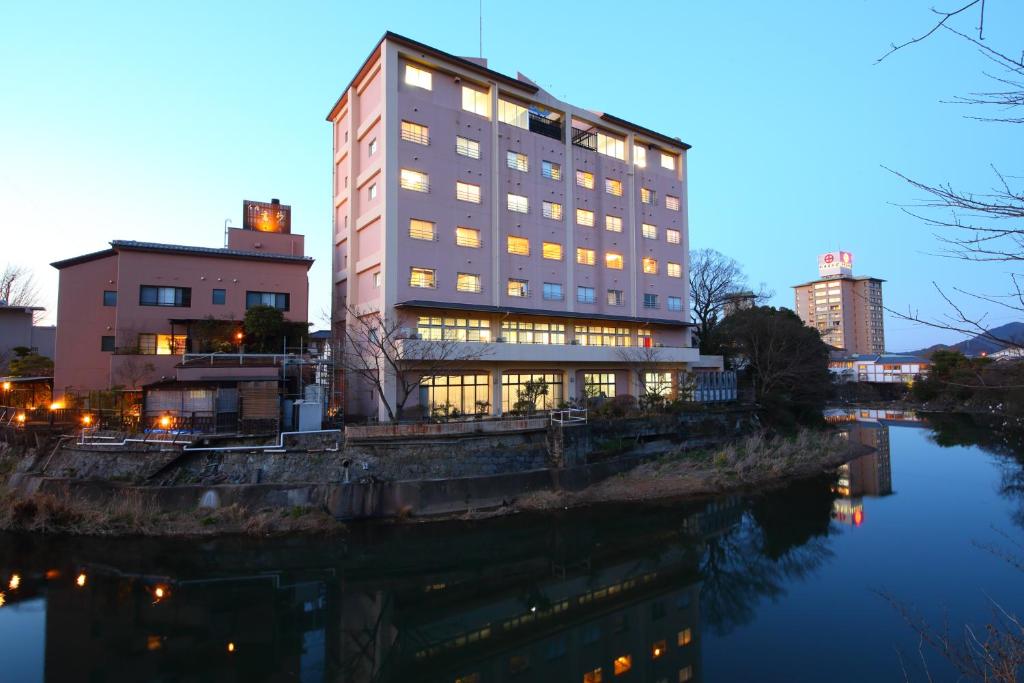 a tall building next to a river at dusk at Koyokaku in Ureshino