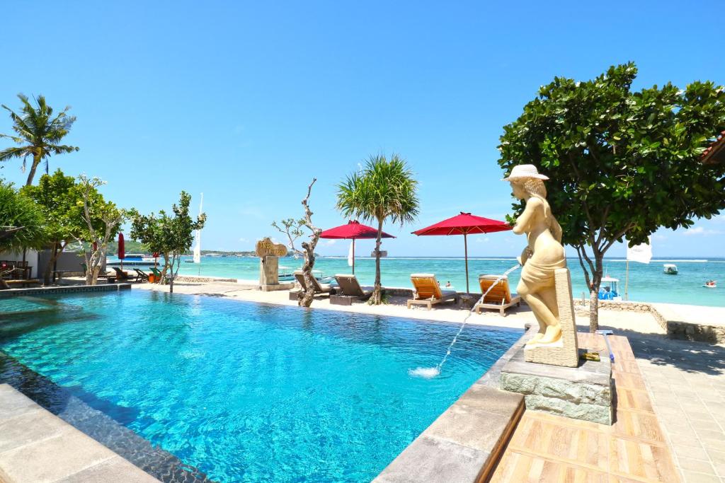 a pool with a statue next to the ocean at Mega Cottages in Nusa Lembongan