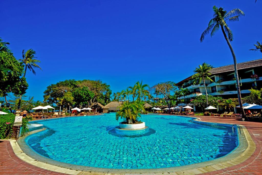 a large pool with a fountain in the middle of a resort at Prama Sanur Beach Bali in Sanur