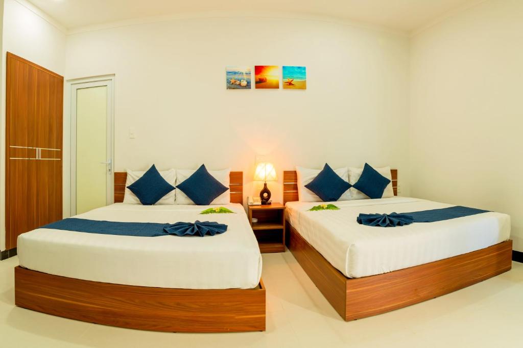 a bedroom with two beds with blue pillows at PHAM GIA HOTEL Mui Ne in Mui Ne