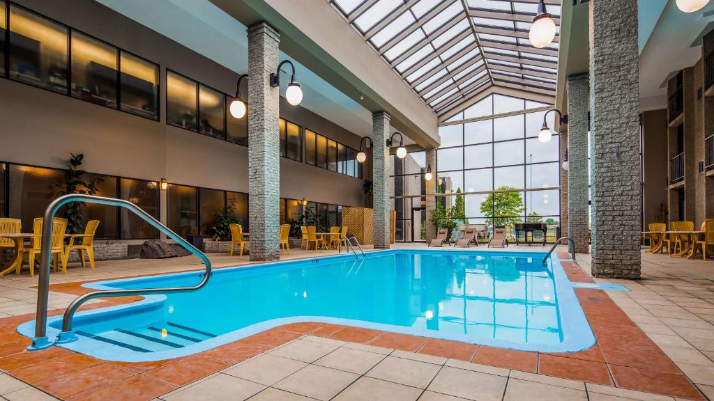 a pool in the lobby of a hotel with tables and chairs at Best Western Hotel Universel Drummondville in Drummondville