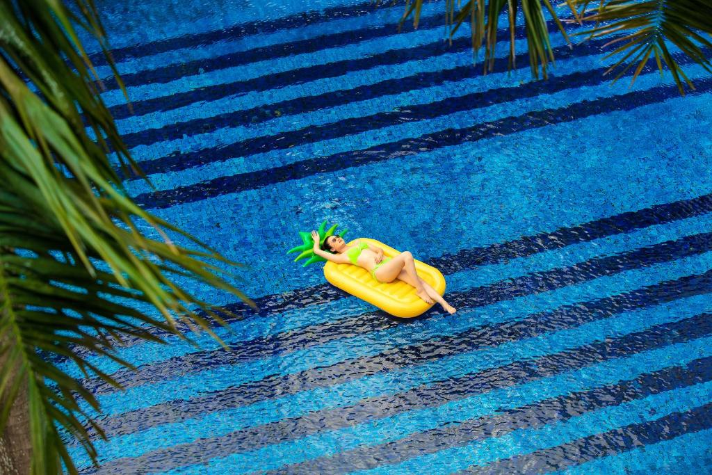 
a yellow surfboard floating on top of a blue pool at Indochine Palace in Hue

