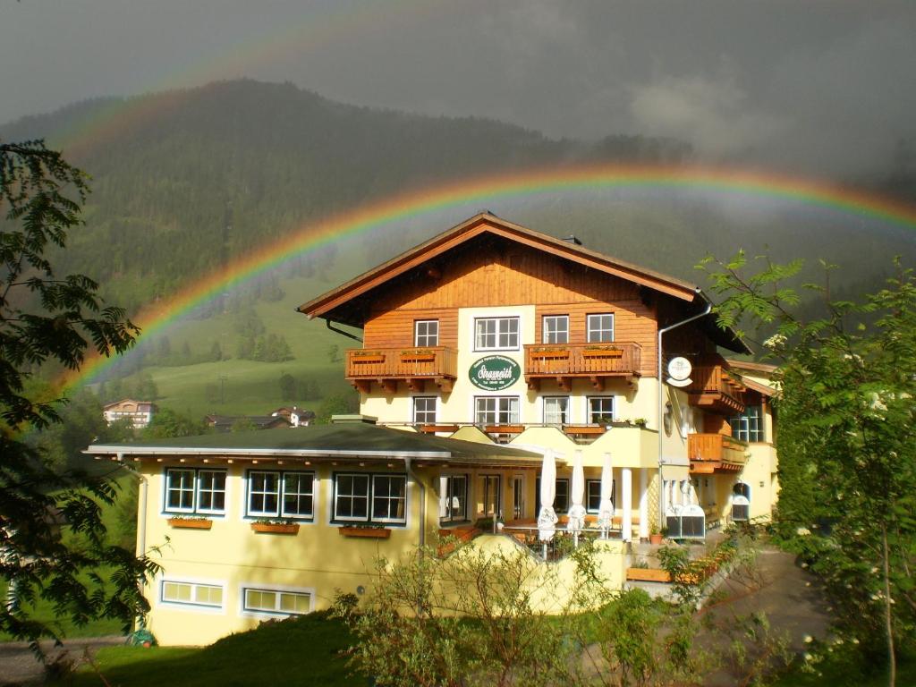 a rainbow is over a house with a rainbow at Gasthof-Pension Strassreith in Werfenweng