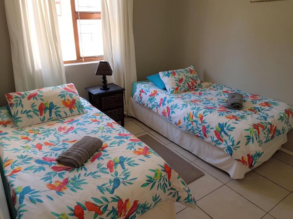 a bedroom with two beds with flowers on them at Serengeti Heide Self Catering Flats in Cape Town