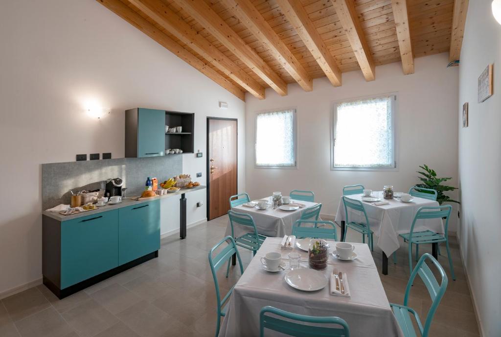 a kitchen and dining room with tables and blue chairs at B&B Terrebianche in Lavagno
