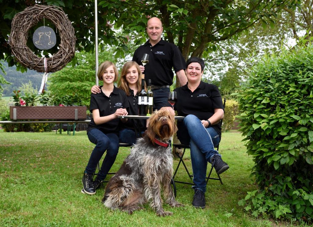 een familie die poseert voor een foto met hun hond bij Weingut Weich in Riol