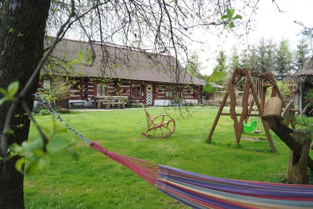 uma rede num quintal ao lado de uma cabana de madeira em Agroturystyka Smolnikowe Klimaty em Smolnik