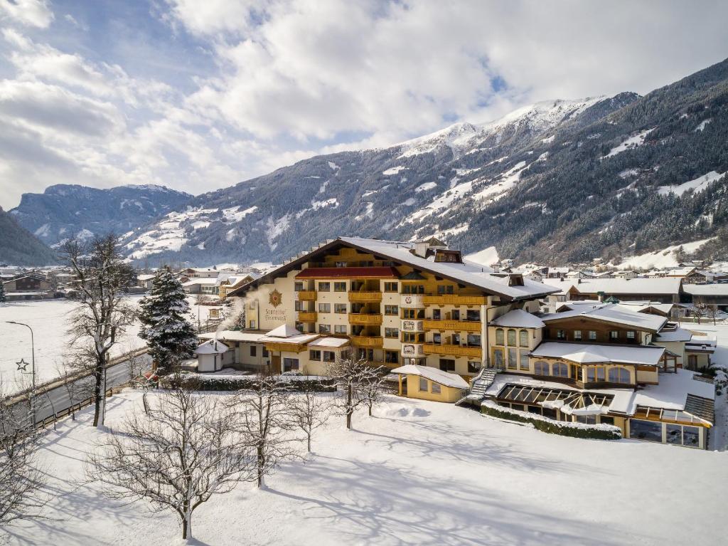 a hotel in the snow with mountains in the background at Ferienhotel Sonnenhof in Zell am Ziller