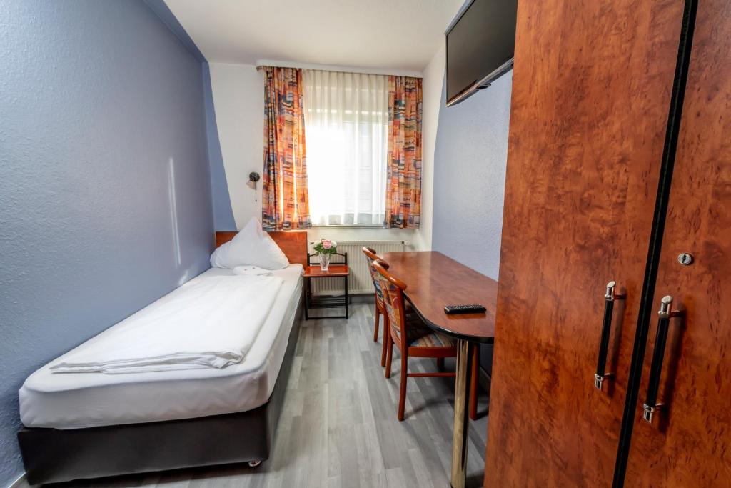 シュトゥットガルトにあるホテル シュテルンのベッドとデスクが備わる小さな客室です。