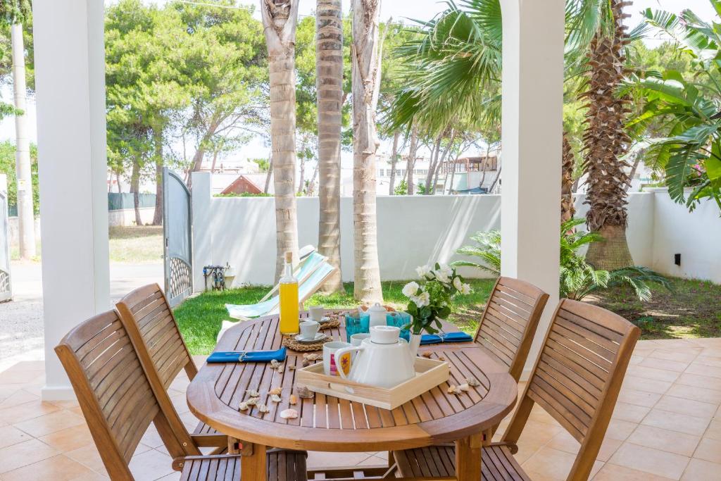 a wooden table and chairs on a patio with palm trees at Villa Ferreri in Specchiolla