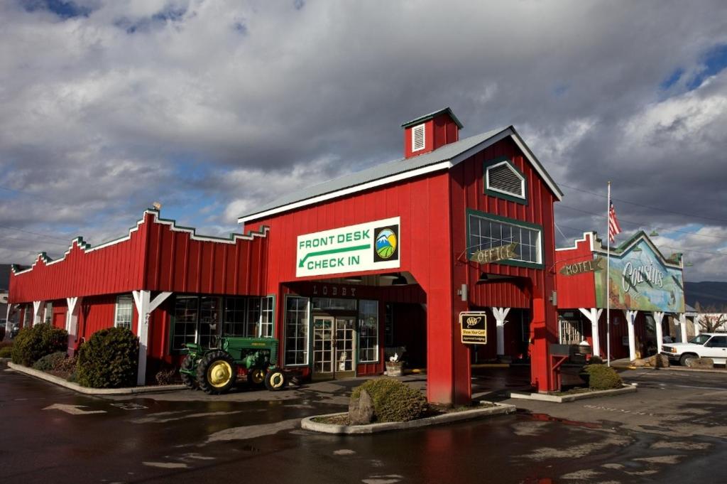 a red building with a tractor in a parking lot at Cousin's Country Inn in The Dalles