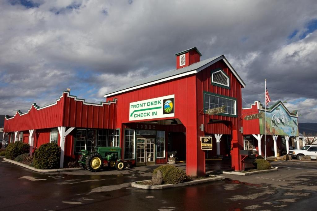 un edificio rosso con un trattore in un parcheggio di Cousin's Country Inn a The Dalles