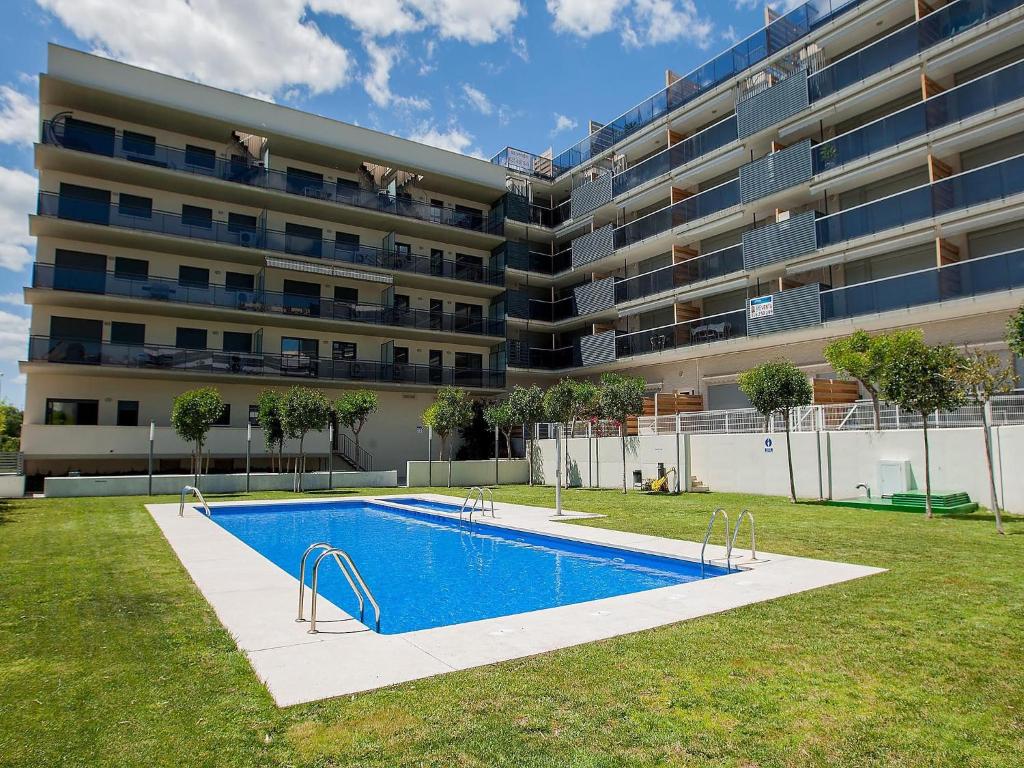 basen przed dużym apartamentowcem w obiekcie For a Stay Las Dunas w mieście Cambrils