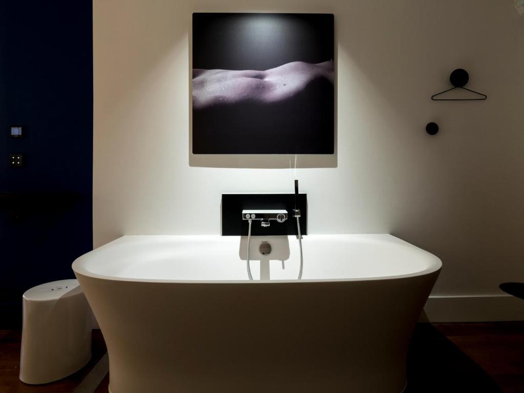 a bath tub in a room with a tv on the wall at MiHotel Vieux Lyon in Lyon