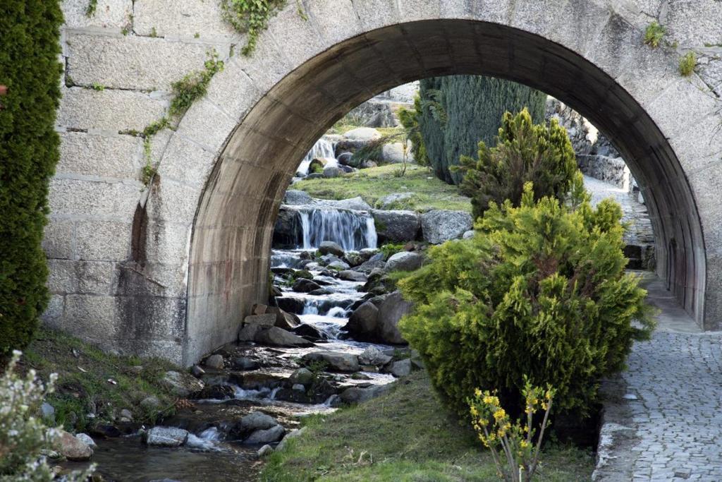 een boog over een stroom water onder een stenen brug bij Doce Lar in Manteigas