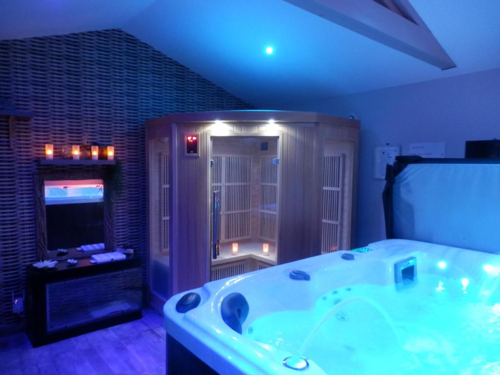 ランブクにあるSuite luxe avec sauna et jacuzzi privéeの広いバスルーム(バスタブ付)、テレビが備わります。