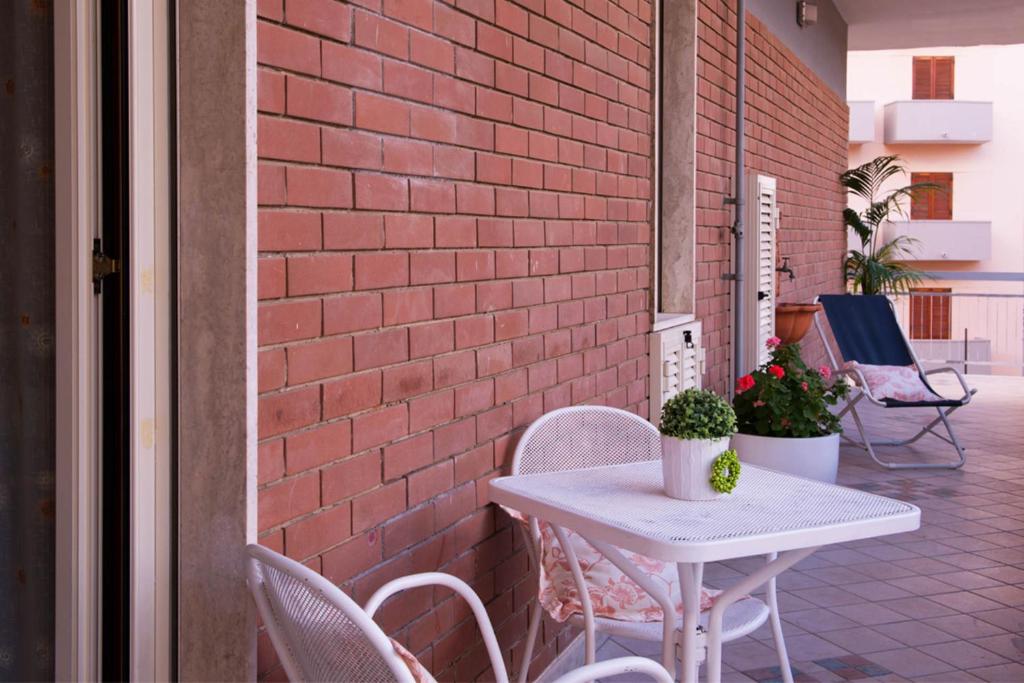 een witte tafel en stoelen naast een bakstenen muur bij Casa Chicco in Sorrento