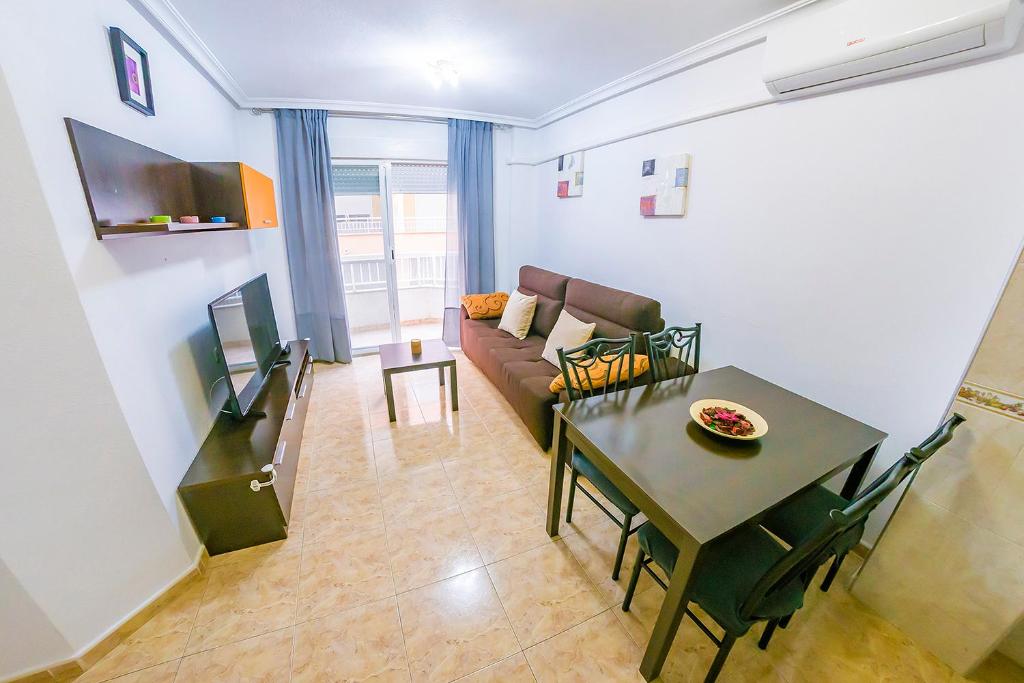 ein Wohnzimmer mit einem Sofa und einem Tisch in der Unterkunft Homely Apartments Noruega in Torrevieja