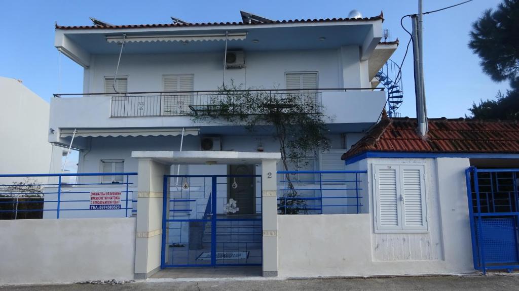 een wit huis met blauwe deuren en een poort bij Kostas Family House in Káto Ássos