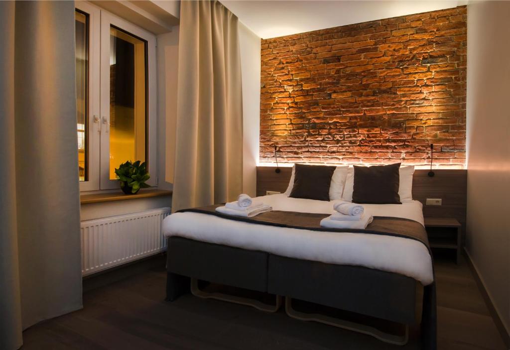 a bedroom with a large bed with a brick wall at Dangė Hotel in Klaipėda