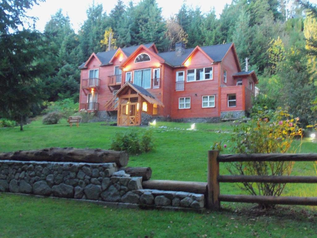 una gran casa roja en una colina con un patio en Hosteria Lekun Lekun en Villa La Angostura