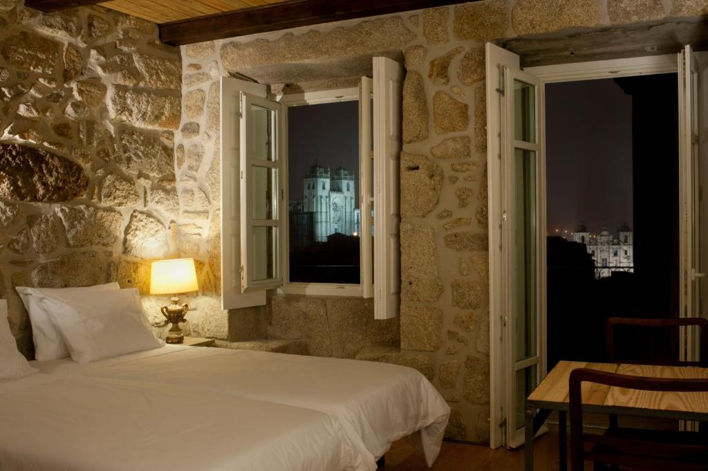 1 dormitorio con cama blanca y ventana en Casa Dos Caldeireiros, en Oporto