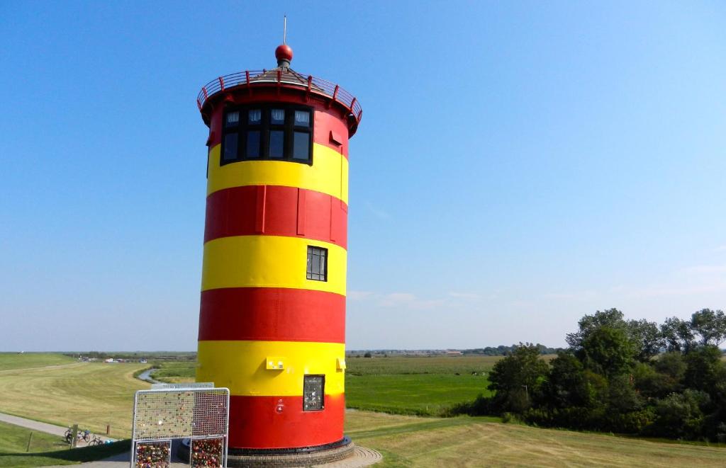 un phare rouge et jaune au milieu d'un champ dans l'établissement Ferienwohnung Krabbenkutter-Greetsiel, à Greetsiel