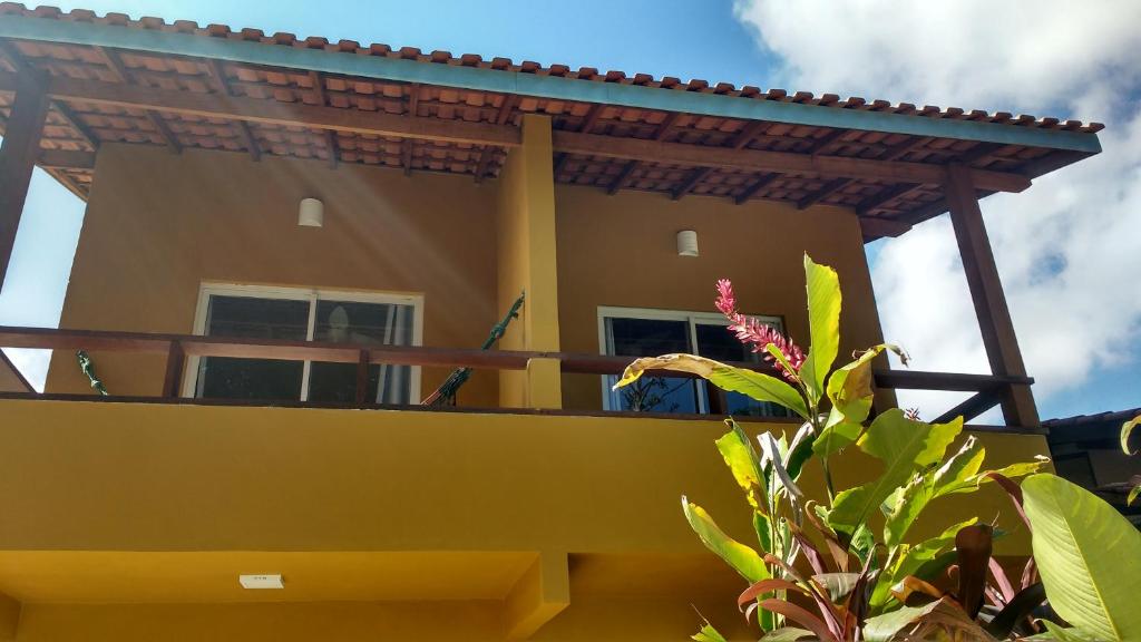 Camburi suites في كامبوري: منزل أصفر مع شرفة