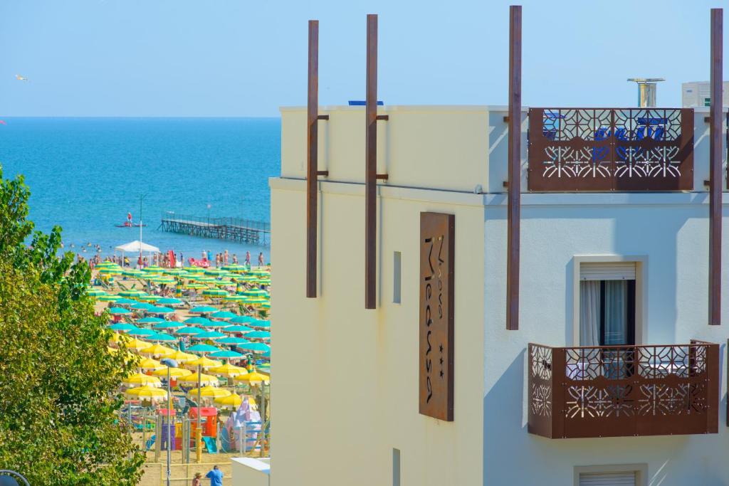 un edificio con balcone e una spiaggia con ombrelloni di Hotel Nuova Medusa Rimini a Rimini