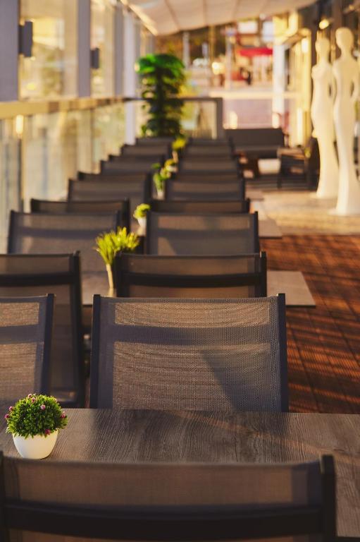 a row of tables and chairs with plants on them at Mercure Lisboa Almada in Almada