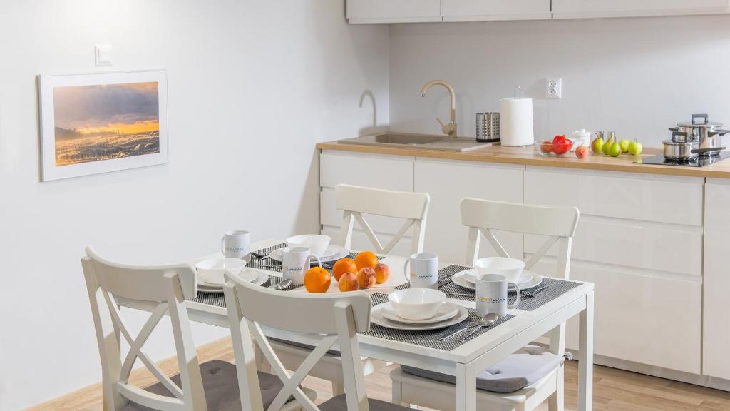 a kitchen with a table and chairs with oranges on it at Piasek i Woda Apartamenty Butikowe in Grzybowo