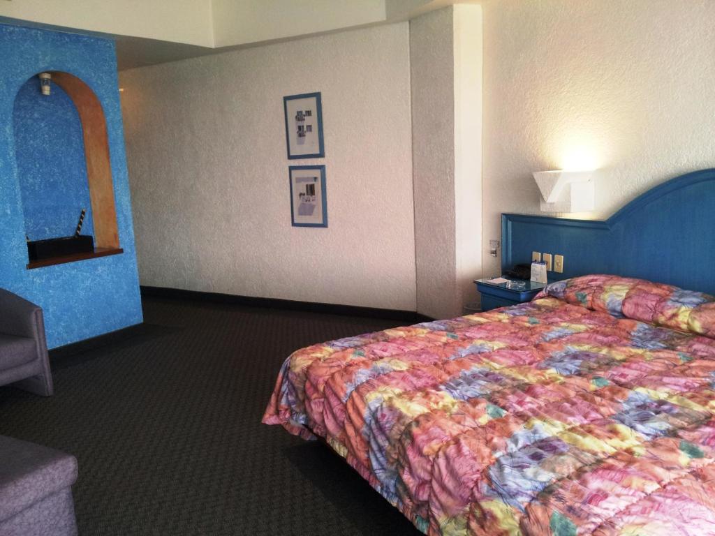Hotel Inn Sur في مدينة ميكسيكو: غرفة في الفندق مع سرير مع لحاف جميل