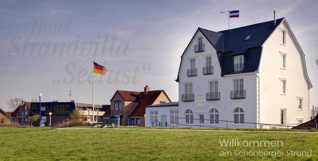 Una gran casa blanca con dos banderas encima. en Strandvilla Seelust, en Schönberger Strand