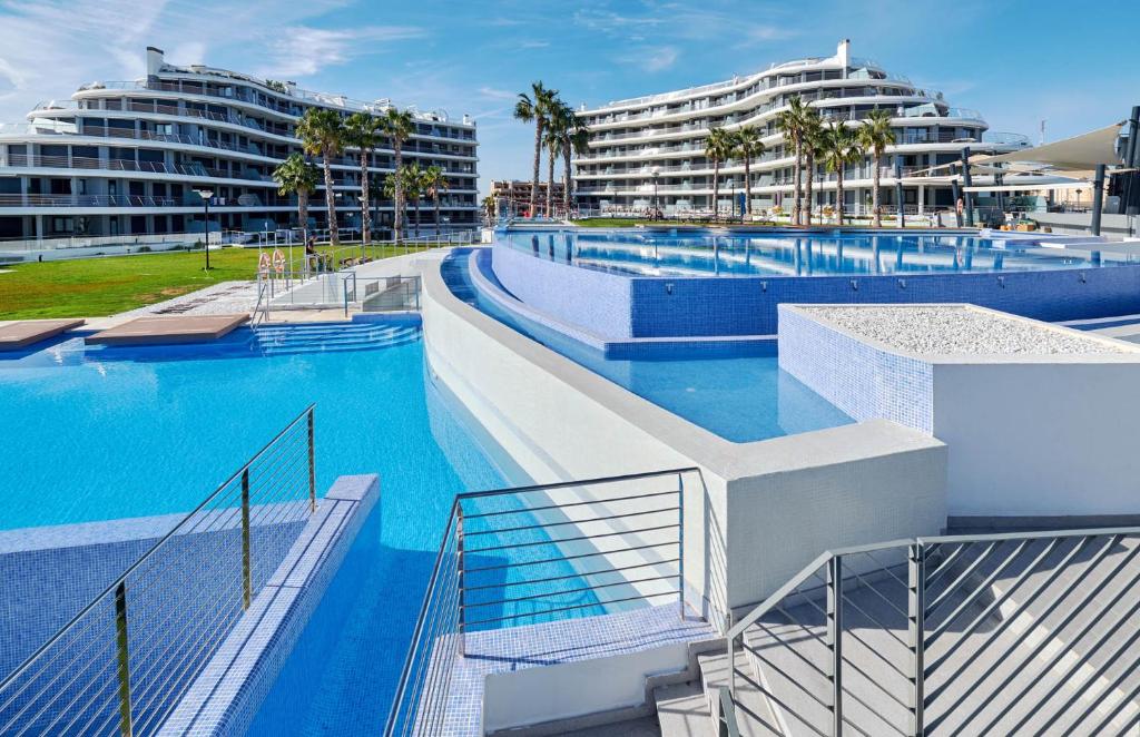 uma grande piscina com dois edifícios ao fundo em Dream Infinity View Apartment em Arenales del Sol