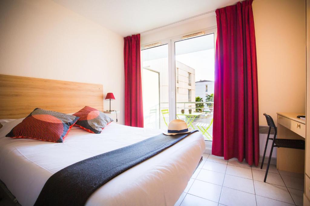 een slaapkamer met een bed met rode gordijnen en een raam bij City Résidence Avignon (5 Epi) in Avignon