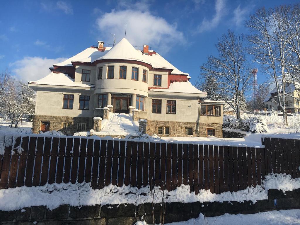 una casa cubierta de nieve frente a una valla en Portus Apartment, en Smržovka