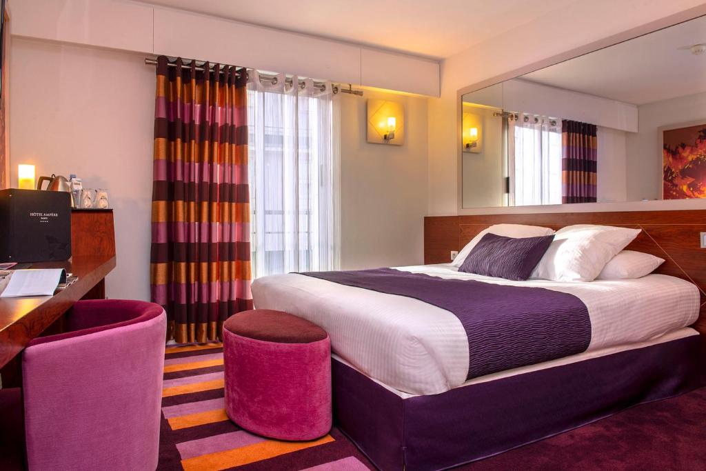 una camera d'albergo con un grande letto e una scrivania di Ampère a Parigi