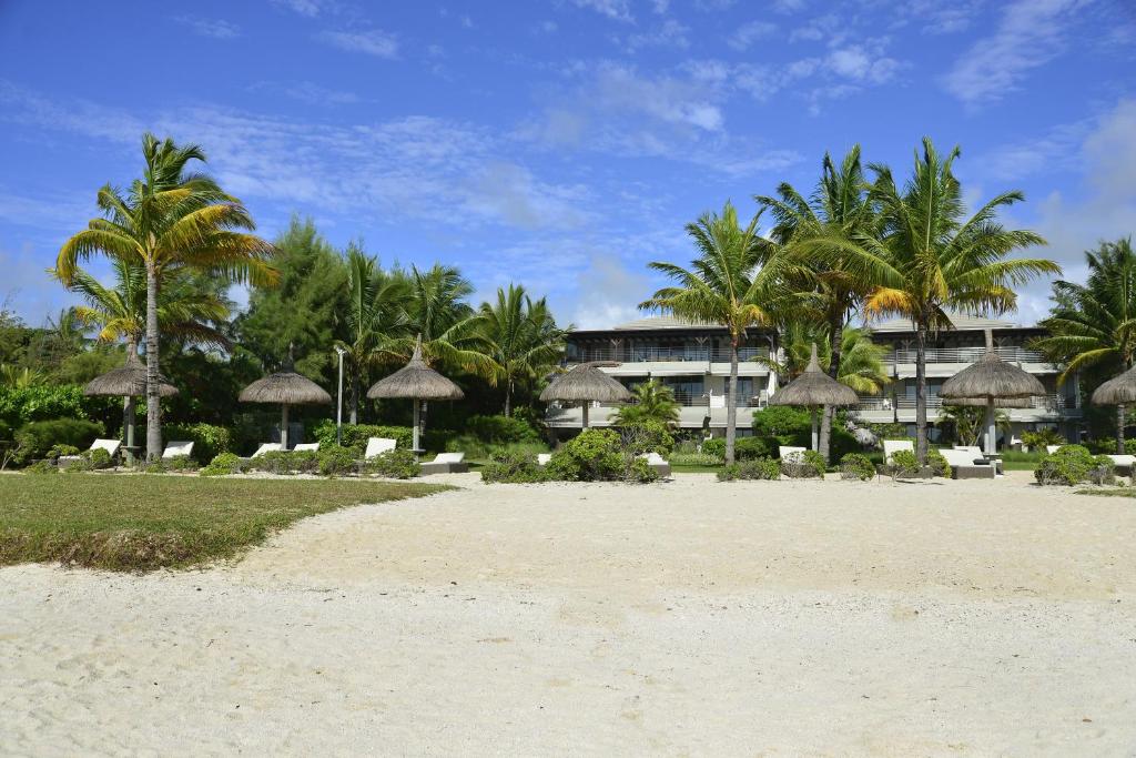 ein Strand mit Sonnenschirmen und Palmen und ein Gebäude in der Unterkunft Sablexotique in Pointe d'Esny